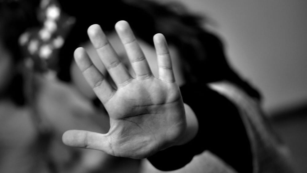 Mano extendida en primer plano, gesto de detener o rechazar. Imagen en blanco y negro con fondo desenfocado